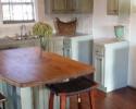 Kitchen with distressed light green cabinets and butcher block island